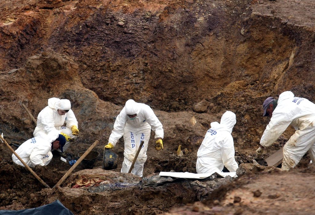 Forensic experts examine a mass grave
